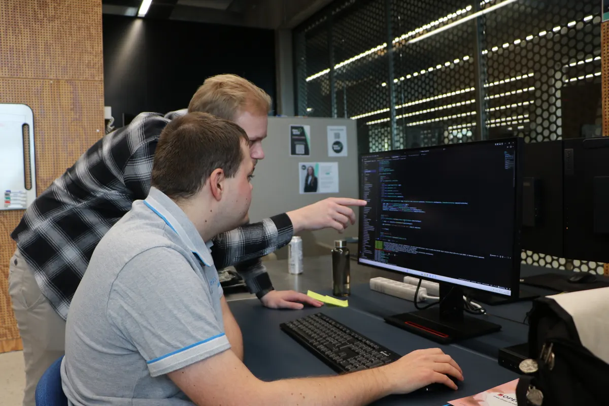 Two students looking at code together on a computer screen