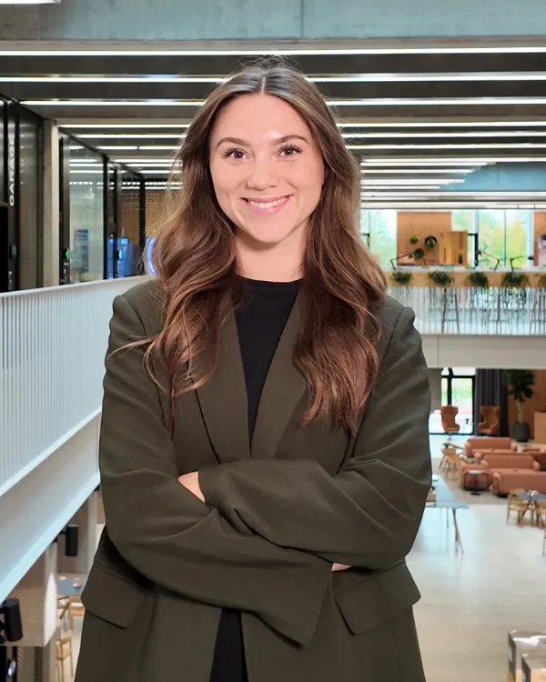 Smiling student with arms crossed in a bright university building