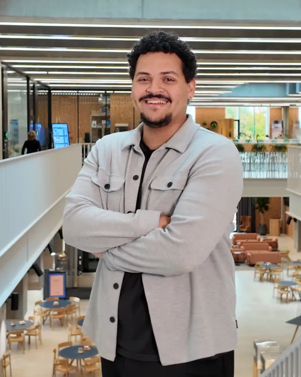Smiling student with arms crossed in a bright university building