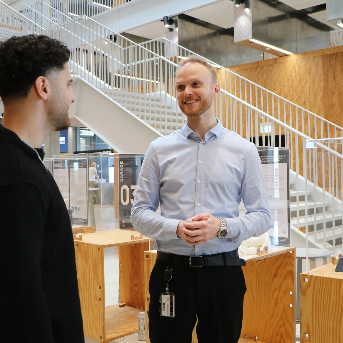 Two people talking by a staircase in a bright university building