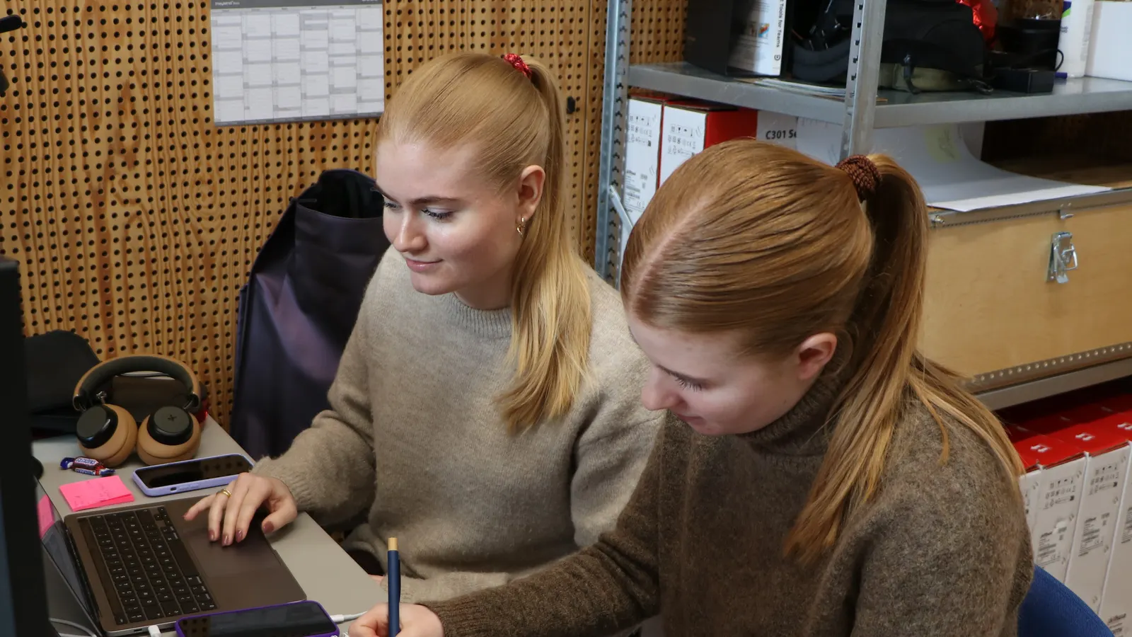 Two people from TrailBlaze working together at a desk with laptops and a notebook